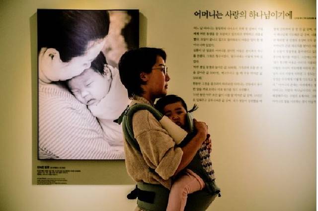 ‘우리 어머니’ 글과 사진전을 관람하는 필자의 모습. 부모가 되어 아이를 안고 전시를 관람하며 어머니의 사랑을 더욱 깊이 체감했다.