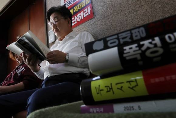 당 대선 후보 단일화를 촉구하며 단식 농성에 돌입한 권성동 국민의힘 원내대표가 8일 오전 서울 여의도 국회 원내대표실 앞에서 ‘히틀러의 법률가들’을 읽고 있다. 권 원내대표의 옆으로 ‘이재명 망언집’, ‘폭정’, ‘두보시선’ 등 책이 보인다. 2025.5.8 뉴시스