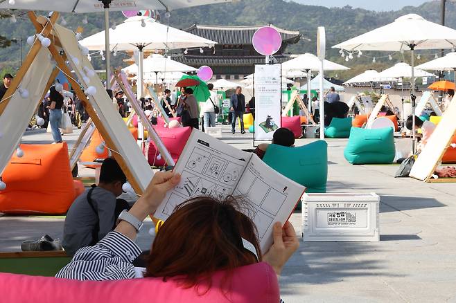 People read books and relax at the outdoor library at Gwanghwamun Square in Jongno District, central Seoul. [YONHAP]