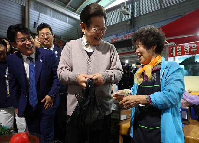 더불어민주당 이재명 대선 후보가 제3차 골목골목 경청투어로 경북지역 방문에 나선 9일 경북 영천시 영천공설시장을 찾아 한 가게에서 영천사랑상품권으로 야채를 구매하고 있다. 연합뉴스&nbsp;