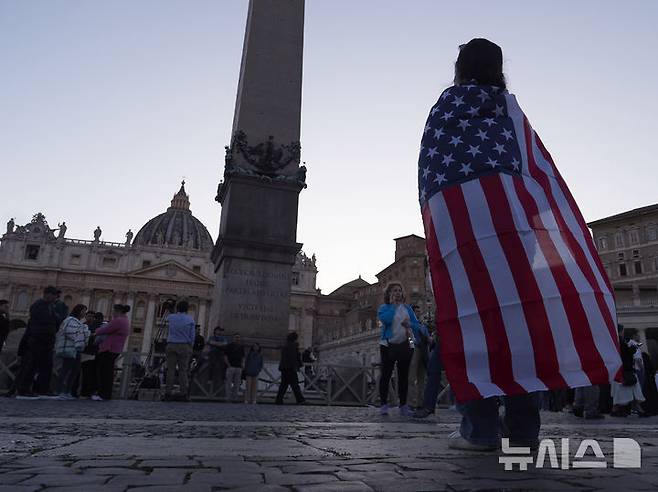 [바티칸=AP/뉴시스] 8일(현지 시간) 미국 출신의 레오 14세 교황이 선출된 뒤 성 베드로 대성당 발코니에 모습을 드러내자 한 신자가 성조기를 두르고 기뻐하고 있다. 2025.05.08.