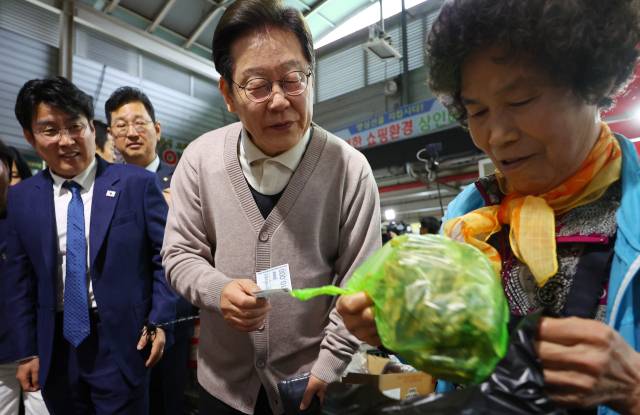 더불어민주당 이재명 대선 후보가 제3차 골목골목 경청투어로 경북지역 방문에 나선 9일 경북 영천시 영천공설시장을 찾아 한 가게에서 영천사랑상품권으로 말린 고추를 구매하고 있다. 연합뉴스