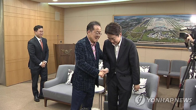 홍준표 전 대구시장이 미국행 여객기에 오르기에 앞서 인천공항까지 배웅을 나온 이준석 개혁신당 대선후보와 손을 맞잡고 있다. <연합뉴스>