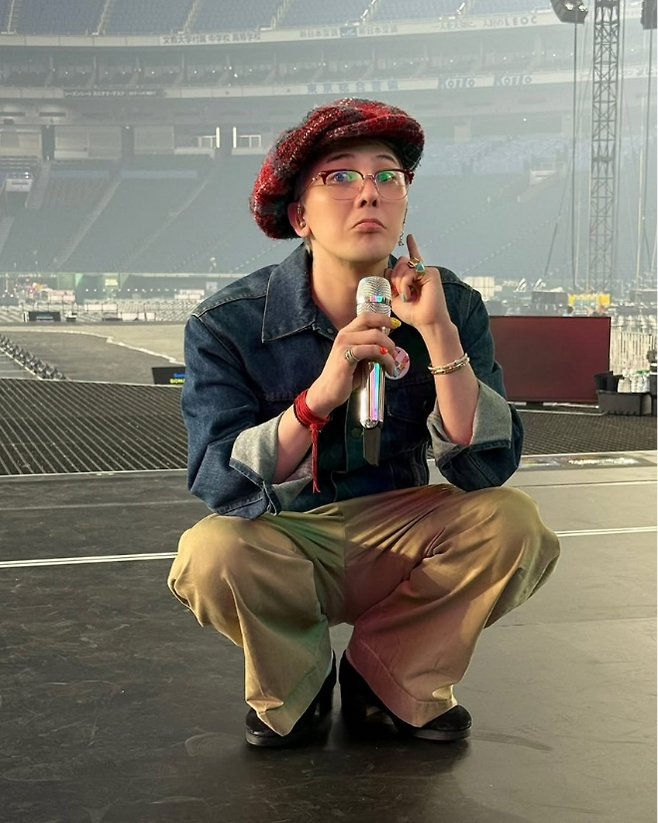 동그랗게 웅크린 채 마이크를 든 지드래곤이 장난기 가득한 표정을 짓고 있다.사진=지드래곤 SNS