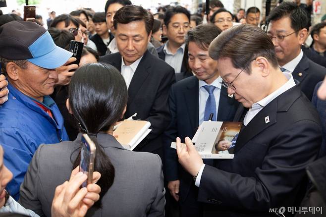 (의령=뉴스1) 이재명 기자 = 경청투어에 나선 이재명 더불어민주당 대통령 후보가 10일 오전 경남 의령군 의령읍 의령전통시장에서 책에 사인하고 있다. 2025.5.10/뉴스1  Copyright (C) 뉴스1. All rights reserved. 무단 전재 및 재배포,  AI학습 이용 금지. /사진=(의령=뉴스1) 이재명 기자