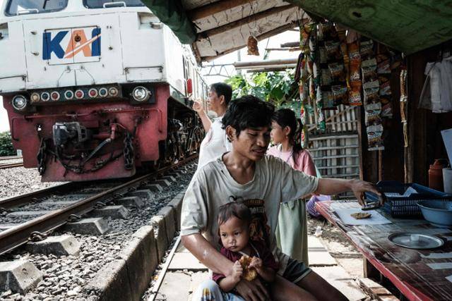 지난달 7일 인도네시아 자카르타의 한 철로에서 한 남성이 딸을 안고 있다. 자카르타=AFP 연합뉴스
