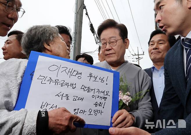 [화순=뉴시스] 조성우 기자 = 민심을 청취하는 '경청 투어'에 나선 이재명 더불어민주당 대선후보가 11일 전남 화순군 화순읍 인근 거리에서 박선영 열사 모친 오영자 씨의 민주유공자법 제정 호소 등 얘기를 듣고 있다. 2025.05.11. xconfind@newsis.com