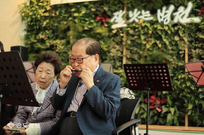 김희수 건양교육재단 설립자와 아내 김영이 여사가 2023년 4월 건양대병원 1층에서 환자와 보호자 앞에서 하모니카 공연하고 있다. (사진=중도일보DB)