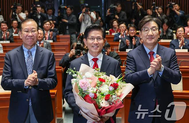 김문수 국민의힘 대통령 후보가 9일 서울 여의도 국회에서 열린 의원총회에서 꽃다발을 받은 뒤 기념 촬영하고 있다. 왼쪽부터 권영세 비대위원장, 김 후보, 권성동 원내대표. 2025.5.9/뉴스1 ⓒ News1 안은나 기자