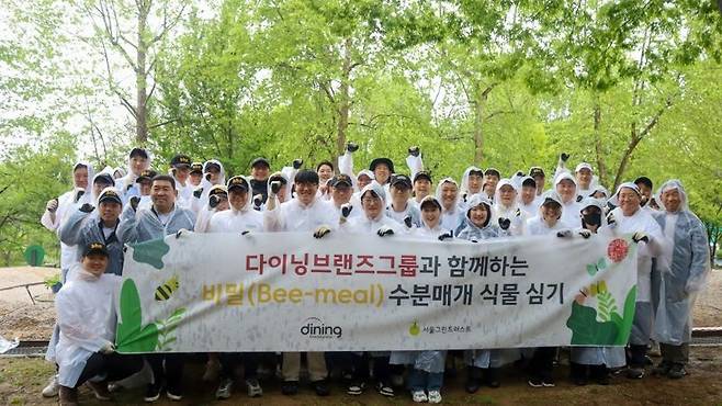 다이닝브랜즈그룹 임직원들이 '수분 매개 식물 심기' 캠페인 단체사진을 촬영하고 있다. 다이닝브랜즈그룹 제공