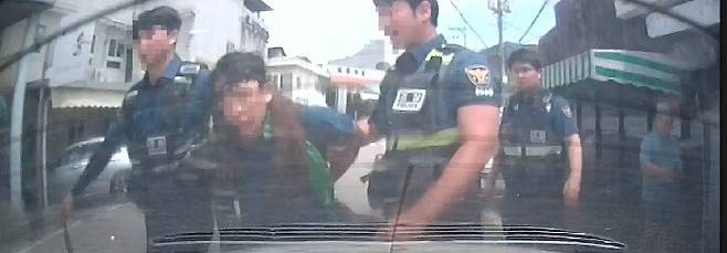 지난해 8월1일 중증 발달장애를 지닌 김준우(가명·가운데)씨가 ‘뒷수갑’을 찬 채로 경찰에 현행범 체포되고 있다. 김씨 가족 제공