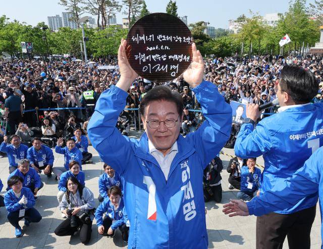 이재명 더불어민주당 대통령 후보가 제21대 대통령 선거 공식 선거운동 첫날인 12일 경기 화성시 동탄 센트럴파크 음악분수중앙광장에서 "세계 1위 반도체 강국 도약!"이라고 쓴 반도체 웨이퍼를 들어 보이고 있다. 화성=뉴스1