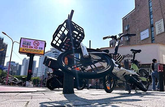 서울 마포구 어울마당로 '홍대 레드로드'에 전기 자전거 등 개인형 이동장치가 보행자들의 통행을 가로막은 채 넘어져있다. 전광판에는 마포구청이 이 곳을 '킥보드 없는 거리'로 지정했다는 안내문을 송출하고 있다. 문희철 기자