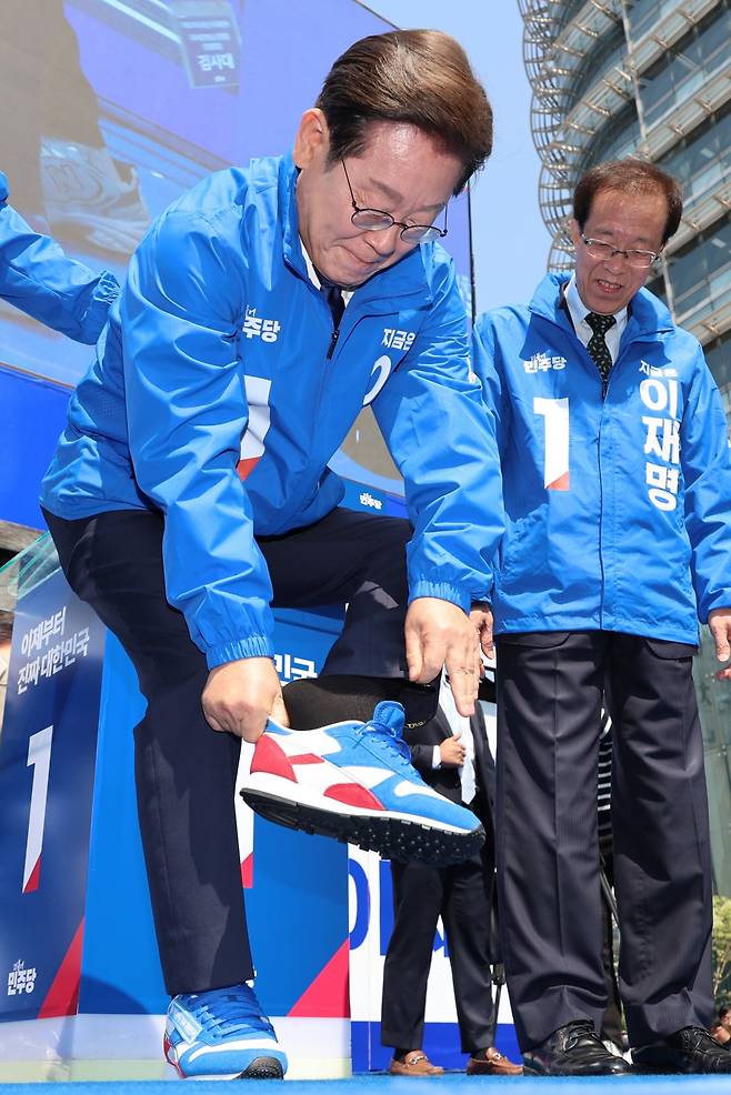 이재명 더불어민주당 대통령 후보가 제21대 대통령선거 공식 선거운동이 시작된 12일 오전 서울 종로구 청계광장에서 열린 중앙선거대책위원회 출정식에서 구두를 벗고 운동화를 신고 있다. / 사진=뉴스1