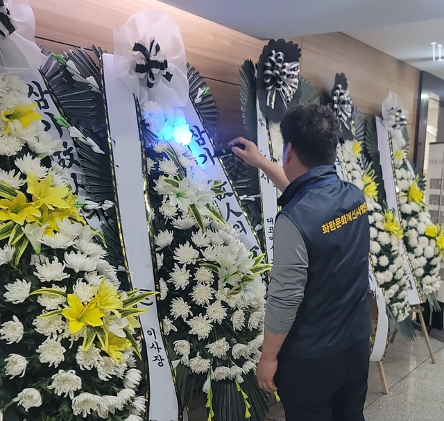 한국화훼자조금협의회 화환문화개선사업단 관계자가 1일 경기 고양지역 한 장례식장에서 화환 재사용 여부를 알기 위해 특수 플래시로 비춰보고 있다. 한국화훼자조금협의회