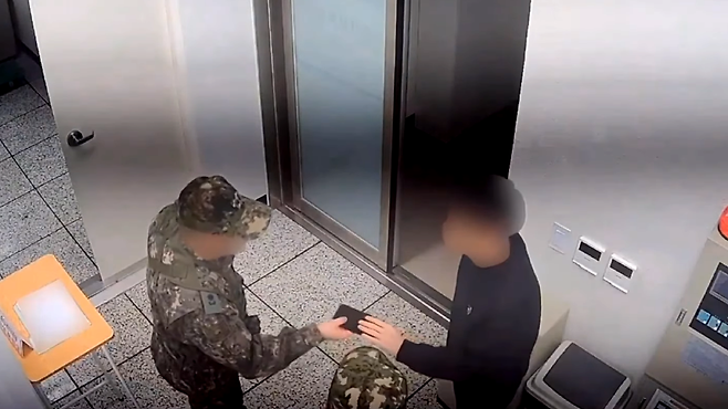 2024년 12월3일 정보사 현장팀이 선관위 당직 근무자의 휴대전화를 압수하고 있다. ⓒ국회 행정안전위원회 제공