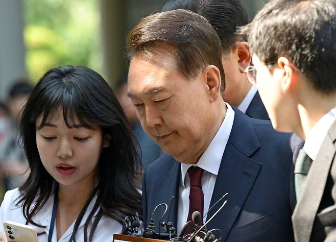 &nbsp;윤석열&nbsp;전 대통령이 12일 서울 서초구 중앙지방법원에서 열린 내란 우두머리 혐의 등 사건 3차 공판에 출석하는 과정에서 취재진들에게 질문 세례를 받고 있다. ⓒ사진공동취재단