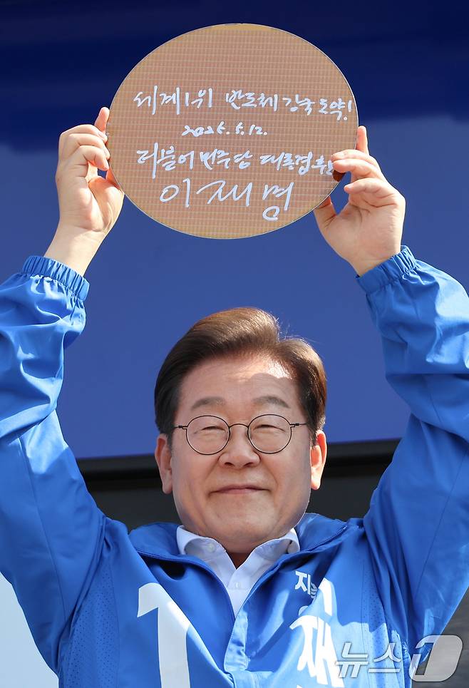 이재명 더불어민주당 대통령 후보가 제21대 대통령 선거 공식 선거운동 첫날인 12일 오후 경기 화성시 동탄 센트럴파크 음악분수중앙광장에서 '세계1위! 반도체 강국도약!'이라고 쓴 반도체 웨이퍼를 들어 보이고 있다. (공동취재) 2025.5.12/뉴스1 ⓒ News1 안은나 기자