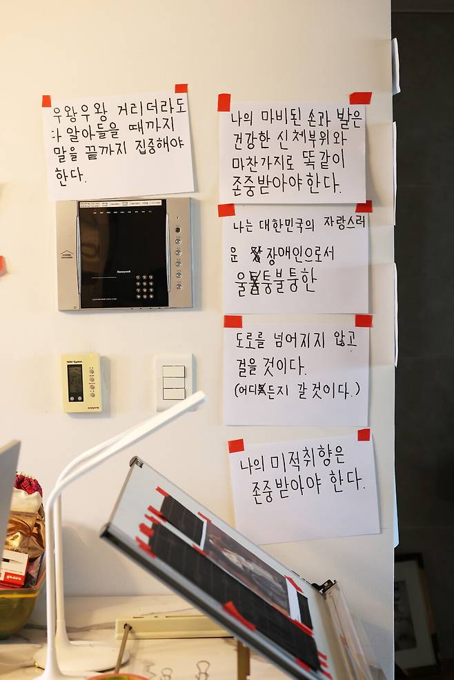 송씨 부부의 벽에 붙은 종이. 오른쪽 마비가 있는 송씨의 남편이 왼손으로 직접 쓴 글씨가 적혀 있다. 류우종 기자.