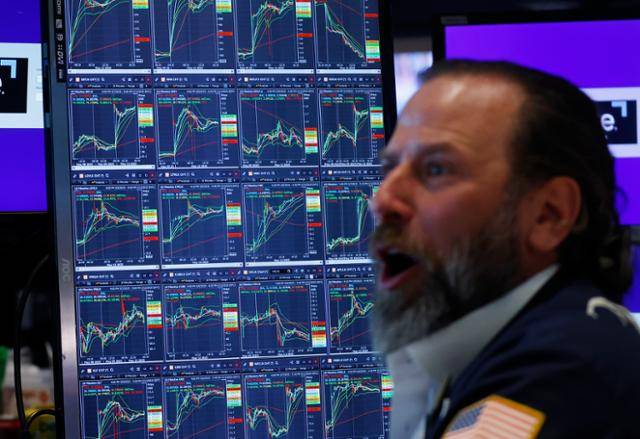 12일 미국 월스트리트 뉴욕증권거래소에서 일하는 트레이더들 뒤로 각종 지수가 급등한 그래프가 보인다. 뉴욕=UPI 연합뉴스