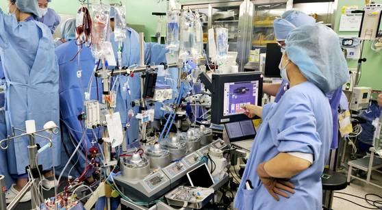 오지영 체외순환사가 환자 상태를 확인하고 있다. 인공심폐기 뒤에선 정의석 교수 등이 심장 수술 중이다. 심장수술 땐 보통 체외순환사 2명이 함께 한다. 채혜선 기자