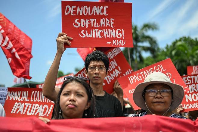 13일 필리핀 마닐라의 한 대로에서 시위대가 전날 실시된 총선 관련 선거 부정을 주장하며 팻말을 들고 규탄 시위를 벌이고 있다.  [AFP연합뉴스]