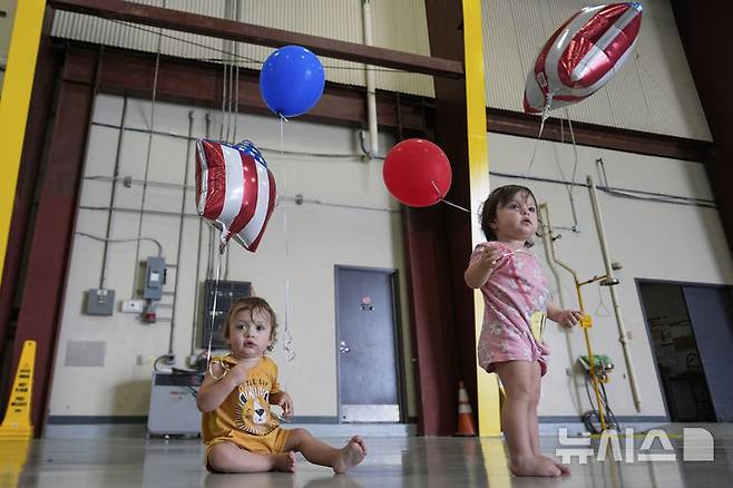 [덜레스=AP/뉴시스] 남아프리카공화국계 아프리카너 아이들이 12일(현지 시간) 미 버지니아주 덜레스에 있는 덜레스 국제공항에 부모와 함께 도착해 풍선을 들고 놀고 있다. 이날 아프리카너(16세기 이후 네덜란드 등 유럽에서 남아공으로 이주해 정착한 백인) 59명이 난민 자격으로 미국에 입국했다. 취임 뒤 사실상 난민 수용을 중단한 도널드 트럼프 행정부가 남아공 백인의 난민 지위를 인정해 미국 내 정착을 허용해 논란이 일고 있다. 2025.05.13.