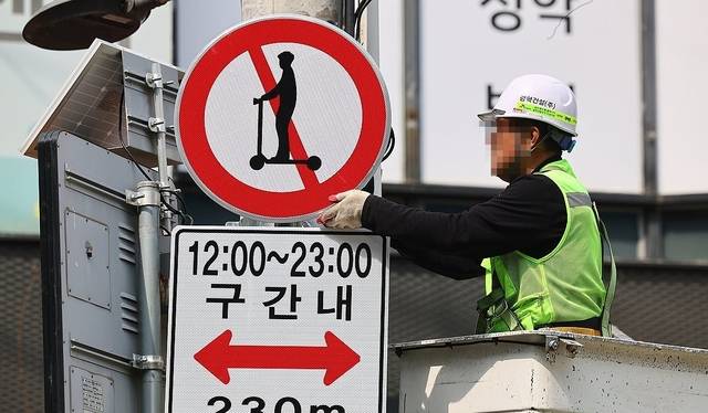 관계자가 ‘킥보드 없는 거리’ 안내판을 설치 중이다. 연합뉴스