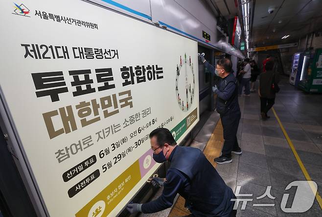 제21대 대통령선거를 20일 앞둔 14일 오전 서울 종로구 지하철 혜화역 승강장 스크린도어에 선관위 관계자들이 대선 홍보물 래핑작업을 하고 있다. 2025.5.14/뉴스1 ⓒ News1 박세연 기자