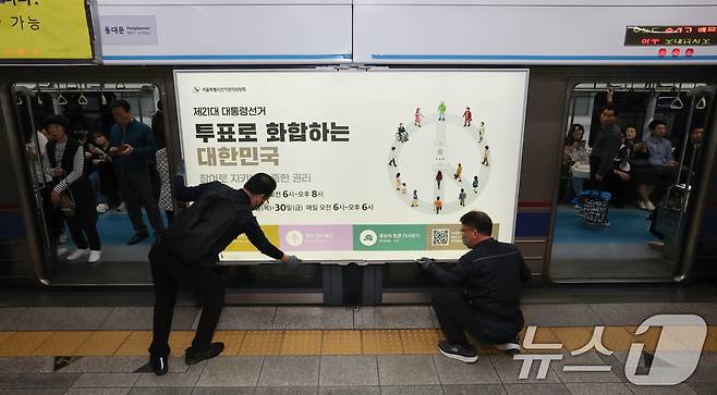 제21대 대통령선거를 20일 앞둔 14일 오전 서울 종로구 지하철 혜화역 승강장 스크린도어에 선관위 관계자들이 대선 홍보물 래핑작업을 하고 있다. 2025.5.14/뉴스1 ⓒ News1 박세연 기자
