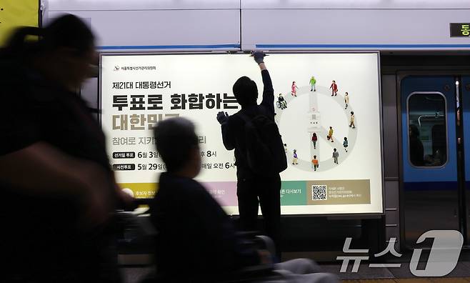 제21대 대통령선거를 20일 앞둔 14일 오전 서울 종로구 지하철 혜화역 승강장 스크린도어에 선관위 관계자들이 대선 홍보물 래핑작업을 하고 있다. 2025.5.14/뉴스1 ⓒ News1 박세연 기자