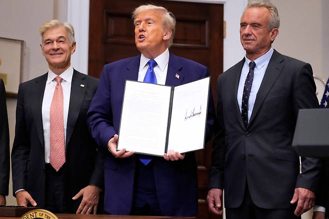 12일(현지 시각) 워싱턴 백악관 루즈벨트 룸에서 도널드 트럼프 대통령이 약물 가격과 관련된 행정명령을 들고 있다. 왼쪽부터 메디케어 및 메디케이드 서비스 센터 관리자 메흐메트 오즈 박사, 트럼프 대통령, 로버트 F. 케네디 주니어 보건복지부 장관 / AP=연합뉴스