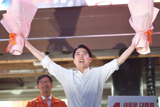 이준석 개혁신당 대선 후보가 5월 12일 서울 청계광장에서 열린 출정식에서 양손에 꽃다발을 들고 지지자를 향해 인사하고 있다. 연합뉴스