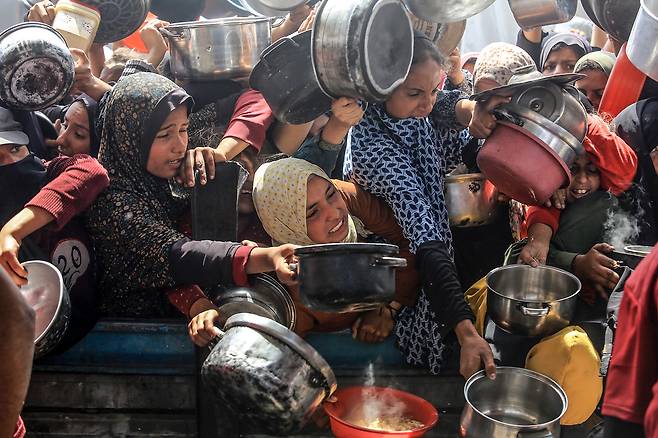 자선 단체들이 12일(현지시간)가자지구 칸 유니스의 알 마와시 지역에서 팔레스타인 주민들에게 식사를 나눠주고 있다. UPI연합뉴스