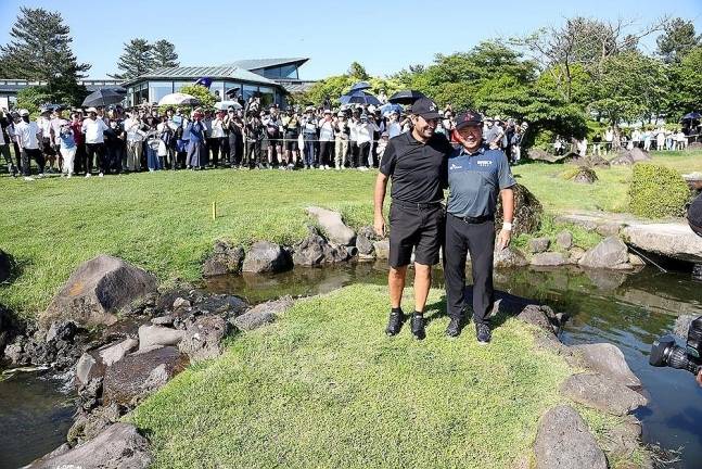 최경주가 지난해 SK텔레콤 오픈에서 정상에 오른 후 우승 발판이 된 18번홀 그린 앞 개울의 섬에서 캐디와 기념 촬영을 하고 있다.    [KPGA 제공]