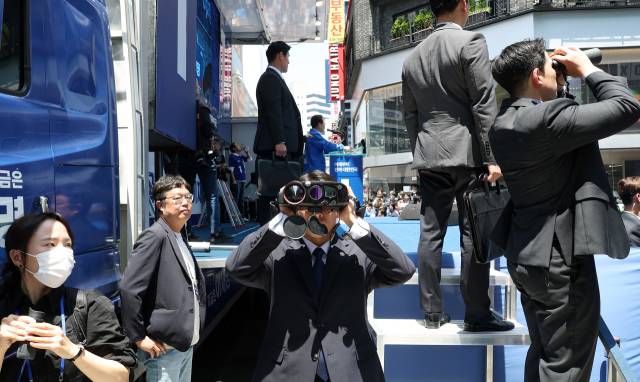 이재명 더불어민주당 대선 후보가 14일 부산 부산진구 서면거리에서 유권자들에게 지지를 호소하고 있는 가운데 경호원이 망원경을 통해 주변을 살피고 있다. 부산=오승현 기자 2025.05.14