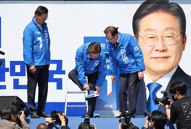 더불어민주당 이재명 대선 후보가 12일 오전 서울 청계광장에서 열린 출정식 및 첫 유세에서 운동화를 갈아 신고 있다. /남강호기자