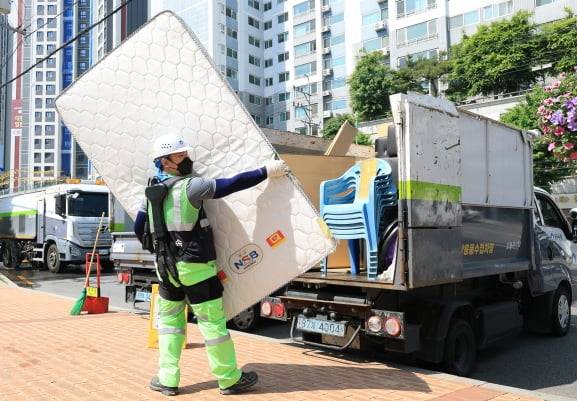 도봉구 한 환경공무관이 ‘입는 로봇’을 입고 침대 매트리스를 차에 옮기고 있다. 도봉구 제공