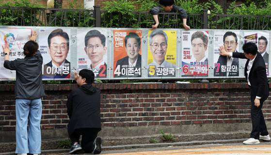 Election officials hang up presidential candidate posters on a wall in Jongno District, central Seoul, on May 15. [NEWS1]