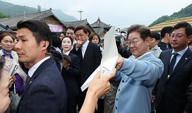 더불어민주당 이재명 대선 후보가 15일 경남 하동군 화개장터 입구에서 유튜브 'K-이니셔TV 케미폭발 동서화합 화개장터 라이브' 오프닝을 마친 후 이동하던 중 지지자가 건네준 김혜경 여사 저서 '밥을 지어요'에 사인해주고 있다. [공동취재] / 사진 = 연합뉴스