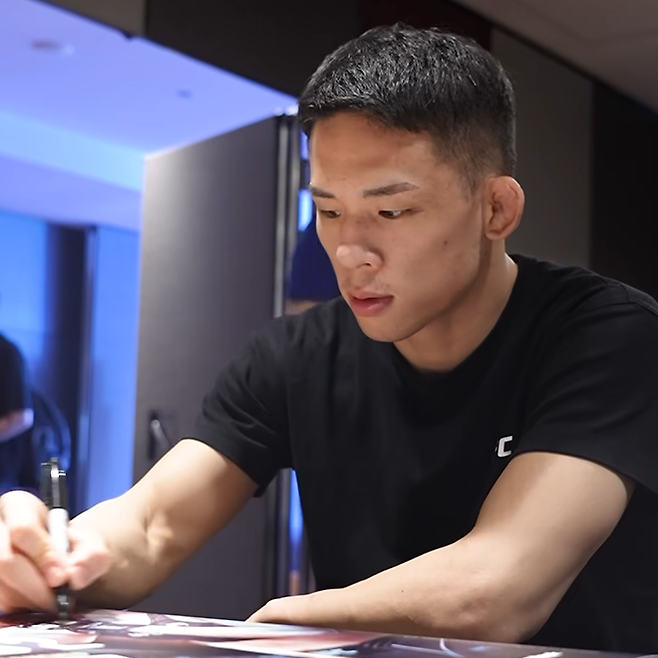 박현성이 2025년 2월 UFC312 호주 시드니 개최 홍보 포스터에 친필로 서명하고 있다. 사진=TKO