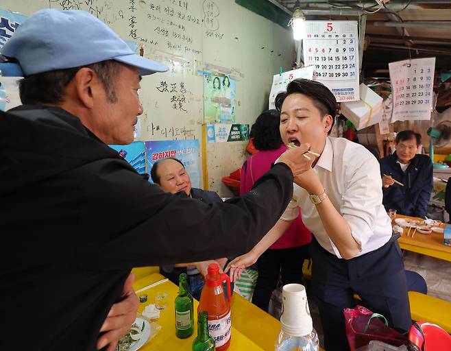 이준석 개혁신당 대선후보(오른쪽)가 지난 14일 부산 자갈치시장을 방문해 지지를 호소하던 중 시민이 준 음식을 먹고 있다. [연합]