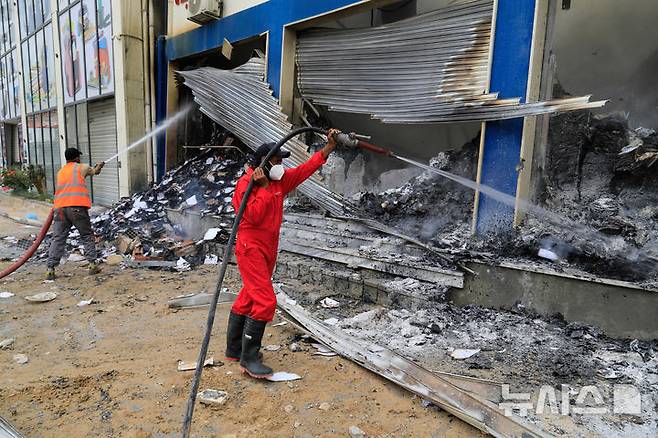 [트리폴리= AP/뉴시스] 무장 군대들 간의 충돌로 파괴된 리비아 수도 트리폴리 거리에서 5월 14일 소방대가 한 서점 화재의 잔불을 끄고 있다.  2025. 05. 15.