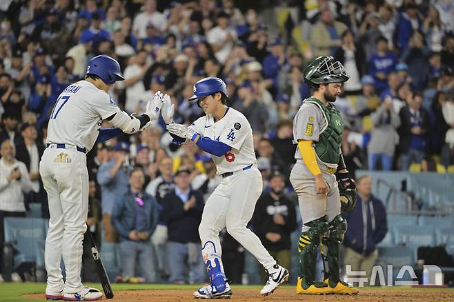 [로스앤젤레스=AP/뉴시스] LA 다저스의 김혜성(가운데)이 14일(현지 시간) 미 캘리포니아주 로스앤젤레스의 다저스타디움에서 열린 2025 메이저리그 애슬레틱스와의 경기 5회 말 동점을 기록하는 1점 홈런(시즌 1호)을 친 후 홈에 들어와 오타니 쇼헤이와 하이 파이브를 하고 있다. 2025.05.15.