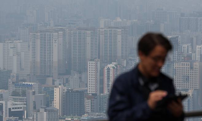 서울 도심 아파트 단지를 배경으로 한 시민이 스마트폰으로 부동산 시세를 확인하고 있다. 뉴시스