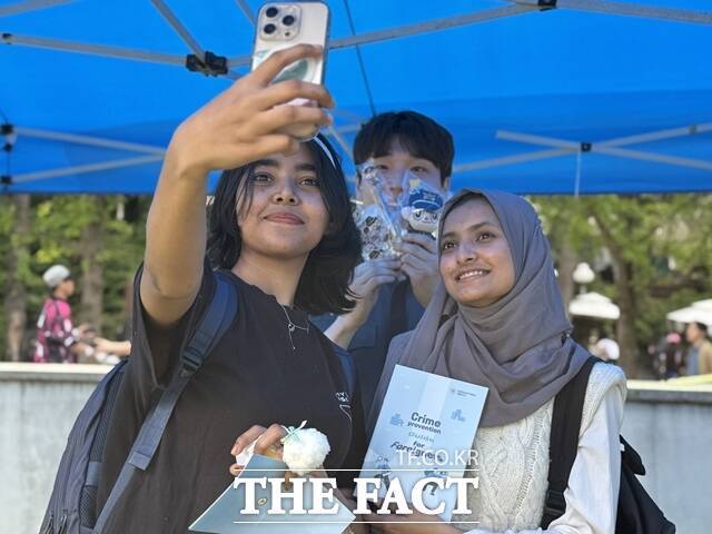 지난 14일 서울 광진구 세종대학교에서 열린 광진경찰서 부스에 참여한 학생들이 범죄 예방 가이드북을 들고 경찰관(가운데)과 기념 촬영을 하고 있다. /정인지 기자