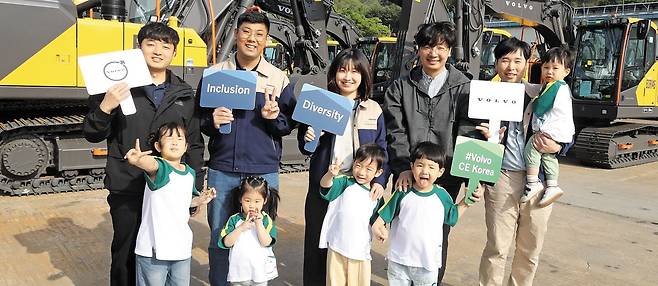 지난 7일 경남 창원시 성산구 볼보그룹코리아 창원 공장에서 회사가 생산한 건설 장비를 배경으로 직원들이 자녀들과 함께 활짝 웃고 있다. 직원들이 든 팻말에 회사 정책인 '다양성 & 포용성(Diversity & Inclusion)'영어 단어가 적혀 있다. 볼보그룹코리아는 직장 어린이집 운영과 자유로운 육아휴직 사용, 유연근무제 도입 등 여성과 가정에 포용적인 기업 문화를 실천하고 있다. /김동환 기자