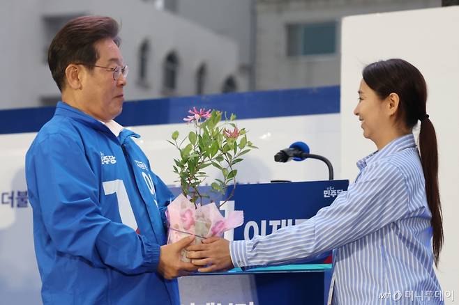 [목포=뉴시스] 권창회 기자 = 이재명 더불어민주당 대선 후보가 15일 전남 목포시 평화광장에서 열린 유세에서 김대중 전 대통령을 상징하는 인동초를 선물받고 있다. 2025.05.15. kch0523@newsis.com /사진=권창회