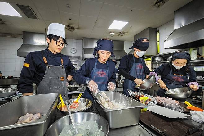 다른 예비 치킨집 사장들과 함께 교육 받은 본지 정시행 기자(왼쪽에서 두 번째)가 반죽옷 입힌 닭을 튀김 가루 트레이에 옮겨담고 있다. 튀기는 시간 10분을 포함, 주문 받은 지 15분 만에 배달로 넘겨야 한다. 위생 마스크는 사진 촬영 때만 잠시 벗었다. /이건송 영상미디어 기자