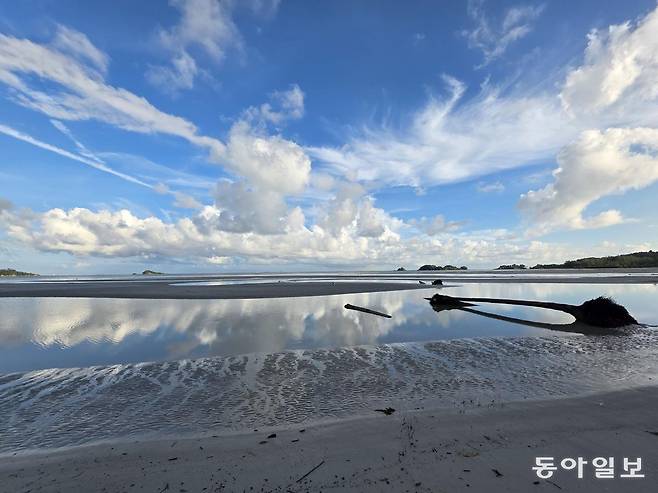 빈탄 라고이 해변의 아침.  물이 고인 해변에 푸른하늘과 흰구름이 비치고 있다.